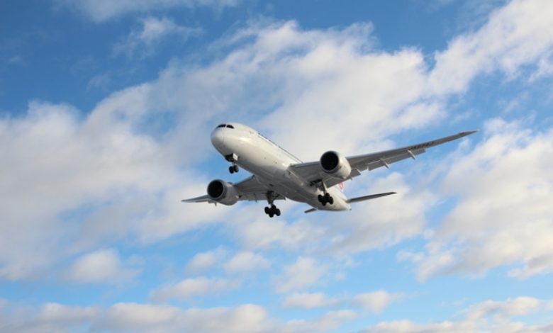 Airplane flying in a blue clouded sky